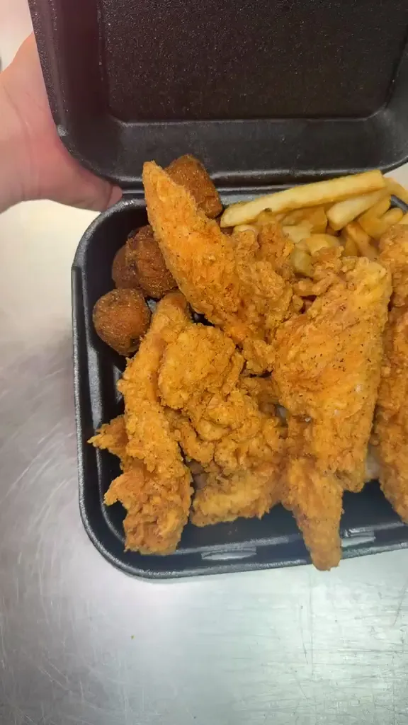 Golden chicken tenders with fries and hush puppies in an open takeout box