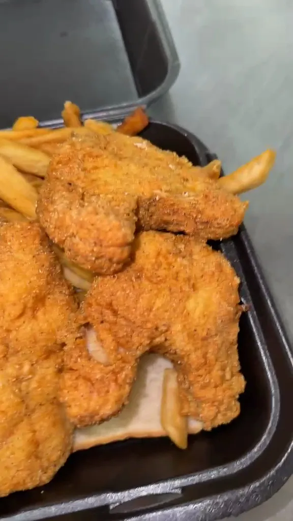 Breaded catfish tenders with fries and white bread in a takeout box
