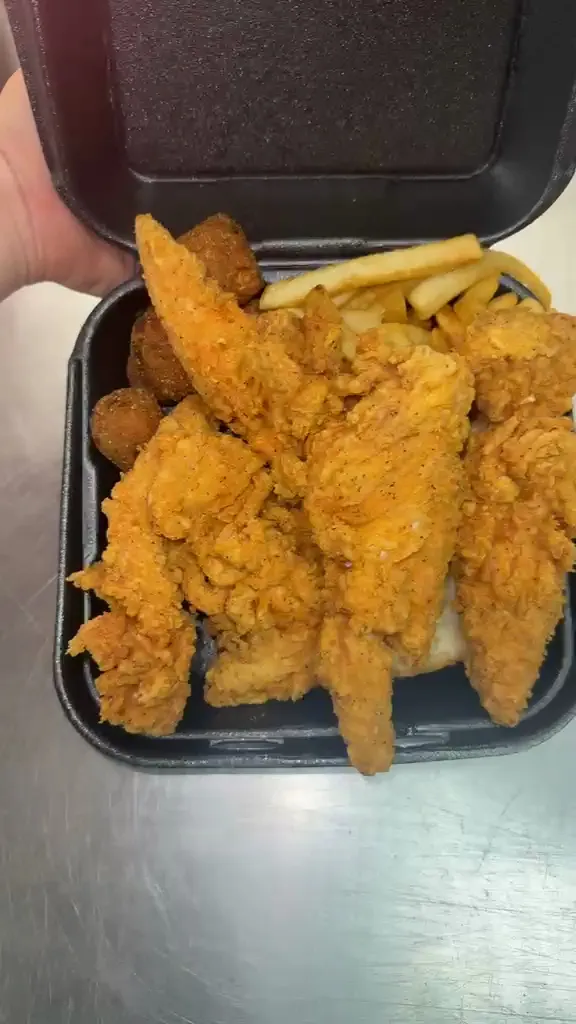 Craggy golden chicken tenders with fries and fried sides in an open takeout box