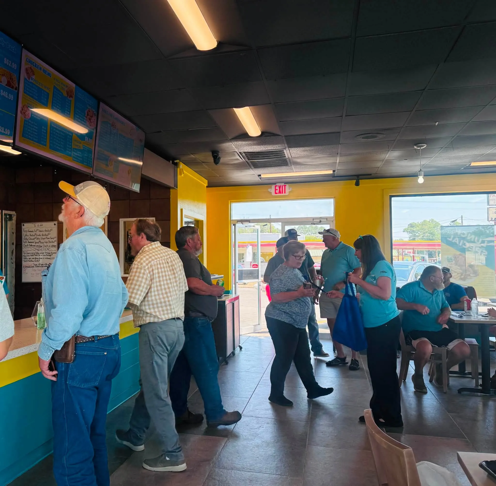 Customers lined up at the Sharks De Queen counter under the illuminated menu boards on opening day