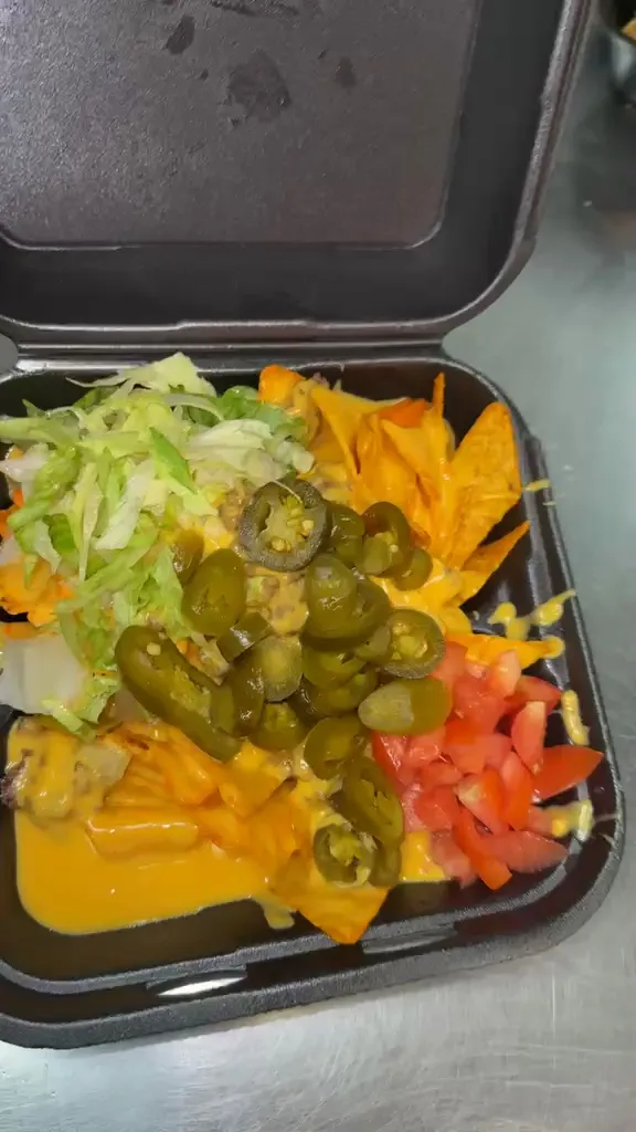 Doritos topped with cheese sauce, lettuce, chopped tomato and jalapenos