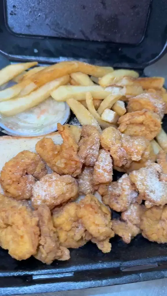 Breaded shrimp with fries, coleslaw and white bread in a takeout box