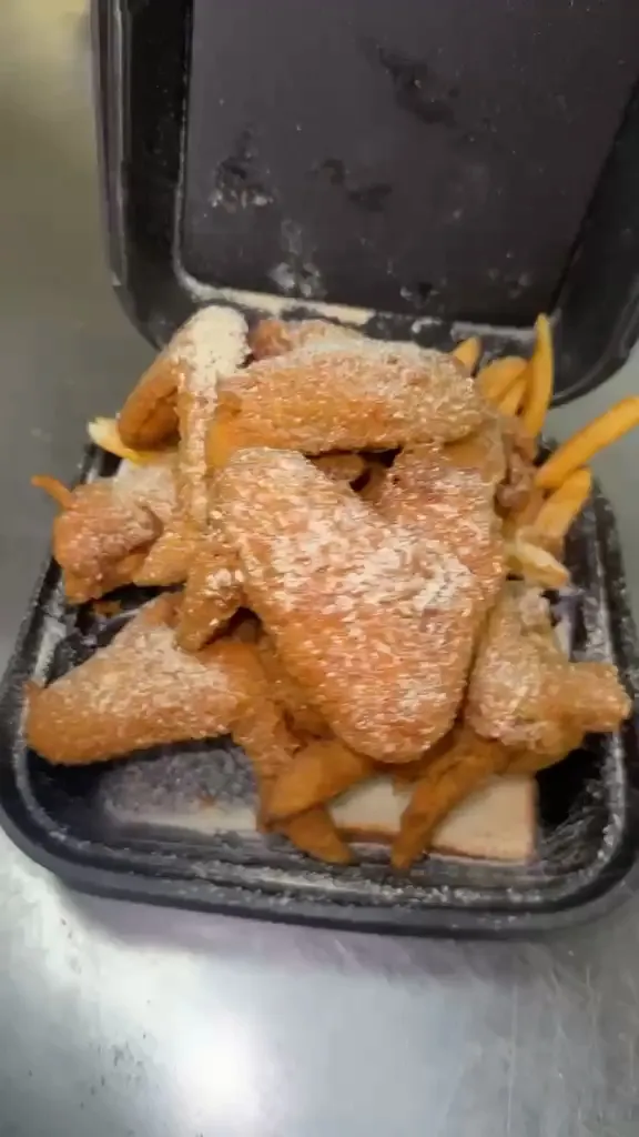 Fried whole wings dusted with seasoning, piled over fries and white bread